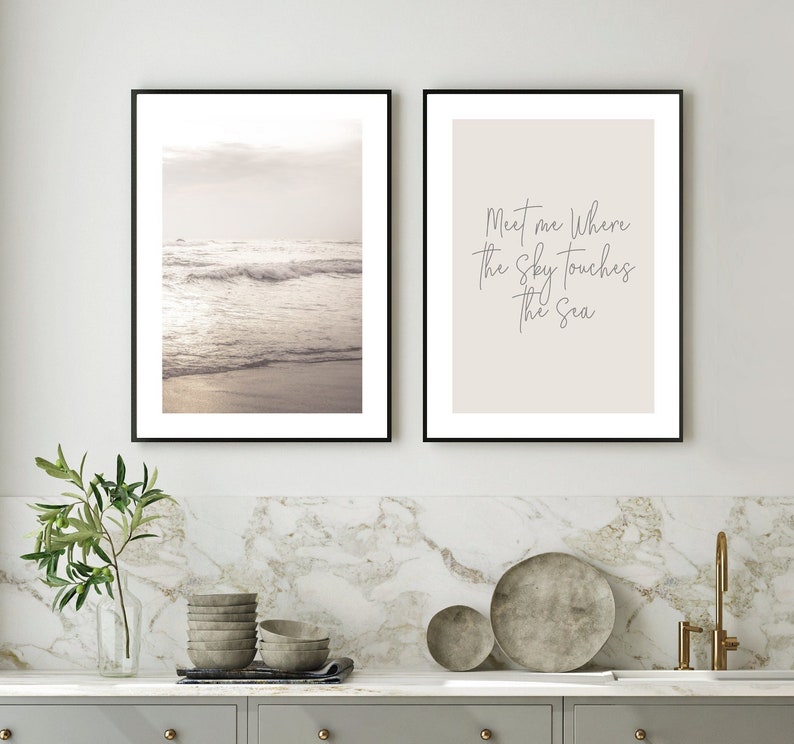 May include: Two framed prints, one with a photograph of a beach scene with waves crashing on the shore and the other with the text "Meet me where the sky touches the sea" in a cursive font.