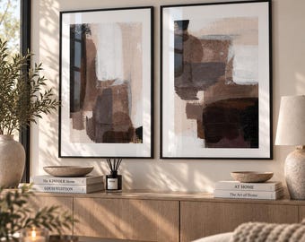 Puede incluir: Dos láminas de arte mural rectangulares en marcos negros finos con pinceladas abstractas en tonos marrón, beige, blanco y gris oscuro. La obra muestra formas geométricas superpuestas y aplicaciones de pintura texturizada.