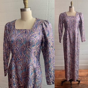 May include: A long-sleeved dress with a square neckline and a metallic brocade pattern in shades of purple, blue, and silver. The dress has puffed sleeves and a fitted silhouette.
