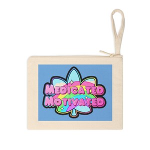 May include: A light beige canvas zippered pouch with a blue background and a pink, blue, and yellow marijuana leaf with the text "medicated motivated" in pink letters.