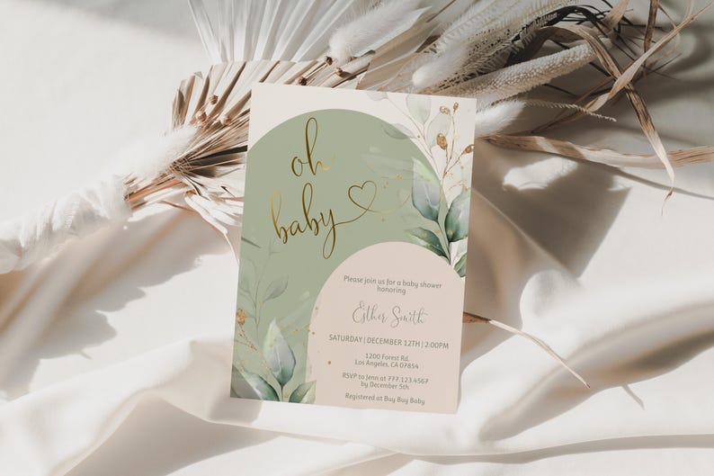 Op de afbeelding: Een rechthoekige uitnodigingskaart voor een babyshower met een saliegroene boog, een beige halve cirkel en aquarel eucalyptusbladeren. De tekst luidt oh baby in gouden cursief met een hartje, gevolgd door de evenementdetails voor Esther Smith.