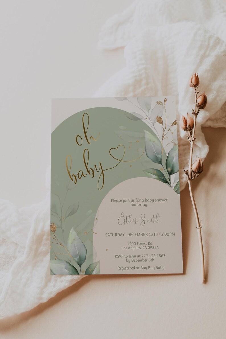 Op de afbeelding: Een rechthoekige uitnodigingskaart voor een babyshower met een saliegroen boogontwerp, goudfolie tekst met oh baby en aquarel eucalyptusbladeren. De kaart bevat de evenementgegevens voor Esther Smith op 12 december om 14:00 uur.