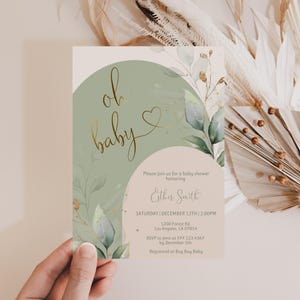Op de afbeelding: Een rechthoekige uitnodigingskaart voor een babyshower met een saliegroene boog, een beige achtergrond en goudkleurige tekst die oh baby leest. Het ontwerp bevat aquarel eucalyptusbladeren en gouden accenten met details in zwarte inkt.