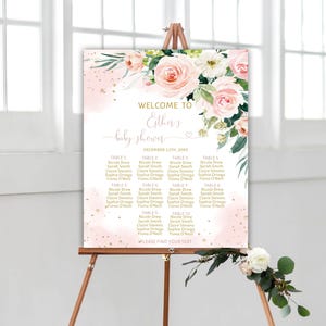 May include: A rectangular baby shower seating chart sign featuring a watercolour floral arrangement of pink roses and green leaves at the top. The text reads Welcome to Esther's baby shower, December 12th, 20XX, and lists tables 1 through 12.