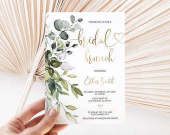 May include: A white rectangular invitation card featuring a watercolor illustration of green eucalyptus leaves on the left side and gold foil text that reads bridal brunch, honoring Esther Smith, with event details and RSVP information included.
