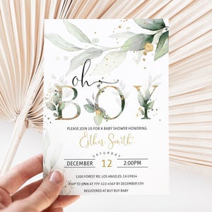 May include: Baby shower invitation with the words "oh boy" in a decorative font, accented with green foliage and gold accents. The invitation includes details for the event, such as the date, time, and location.