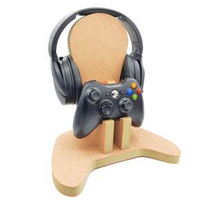 May include: A wooden stand shaped like a video game controller with a black headset and a black video game controller on top.