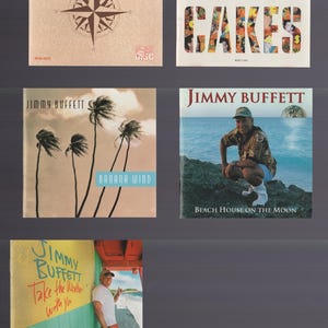 Pode incluir: Coleção de capas de álbuns de Jimmy Buffett. Inclui "Fruitcakes" com letras coloridas, "Banana Wind" com palmeiras, "Beach House on the Moon" e "Take the Weather With You".