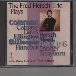 May include: CD cover featuring a photo of a man in a black shirt, with the text "The Fred Hersch Trio Plays" and a list of musicians including Coleman, Coltrane, Davis, Ellington, Hersch, Gillespie, Rollins, Hancock, Shorter, and Strayhorn.
