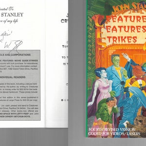 以下が含まれることがあります： 「John Stanley's Creature Features Movie Guide Strikes Again」の表紙には、クラシック映画のモンスターのカラフルなイラストが描かれています。タイトル、著者の名前、そして「Fourth Revised Version Coded for Videos/Lasers」というフレーズが含まれています。