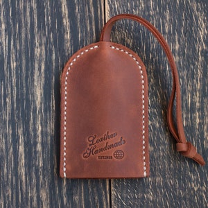 May include: Brown leather key fob with white stitching and the text "Leather Handmades Est.2013" and a globe icon.