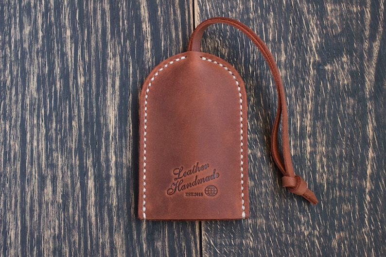 May include: Brown leather key fob with white stitching and the text "Leather Handmades Est.2013" and a globe icon.