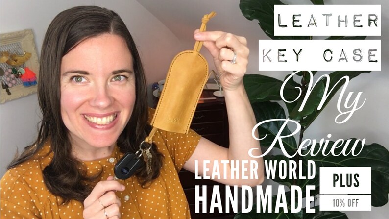 Op de afbeelding: Een vrouw houdt een gele leren sleutelhanger vast met een sleutelring en sleutels. De sleutelhanger is handgemaakt door Leather World. De tekst "LEATHER KEY CASE My Review LEATHER WORLD HANDMADE PLUS 10% OFF" staat op de achtergrond.