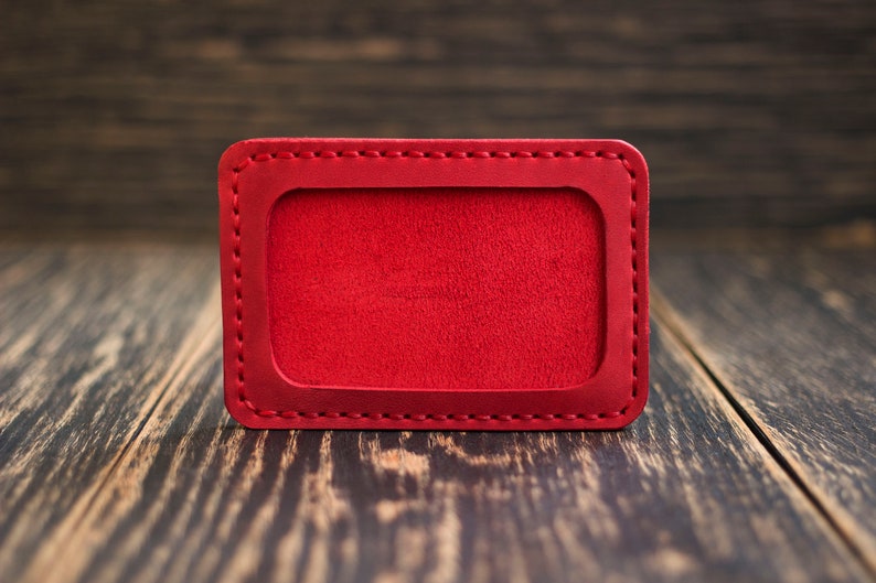 May include: A red leather ID card holder with a stitched border. The holder is empty and ready for personalization.
