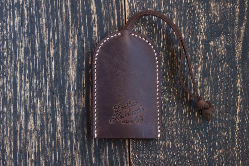 May include: A brown leather key fob with white stitching and the text "Leather Handmades EST.2013" embossed on the front.