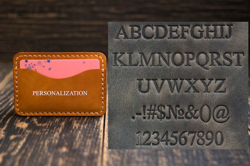 May include: A brown leather card holder with a pink insert and the word "PERSONALIZATION" embossed on the front. A sample alphabet and numbers are shown on a separate piece of leather.