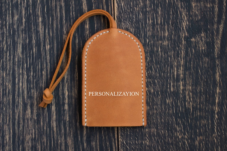 May include: A brown leather key chain with a white stitched border and the word "PERSONALIZATION" embossed in white.