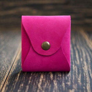 Pode incluir: Um pequeno envelope de couro rosa brilhante com fecho de bot&atilde;o de lat&atilde;o.