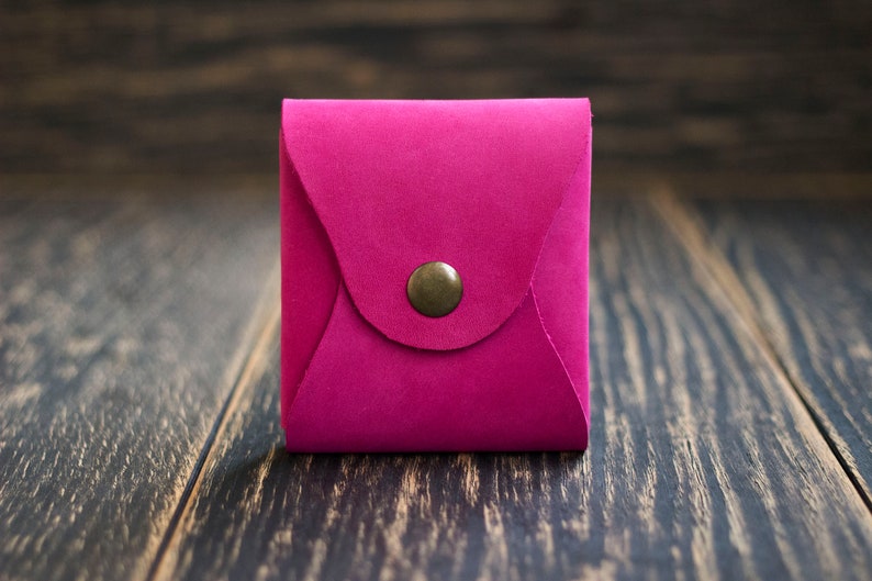 Pode incluir: Um pequeno envelope de couro rosa brilhante com fecho de bot&atilde;o de lat&atilde;o.