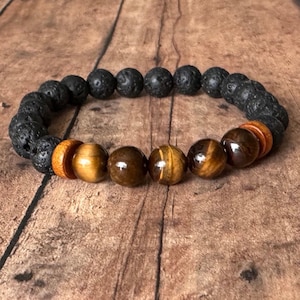 May include: A beaded bracelet with black lava rock beads, brown tiger's eye beads, and wooden beads.