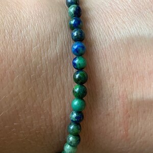 May include: A green and blue gemstone bracelet with small round beads.