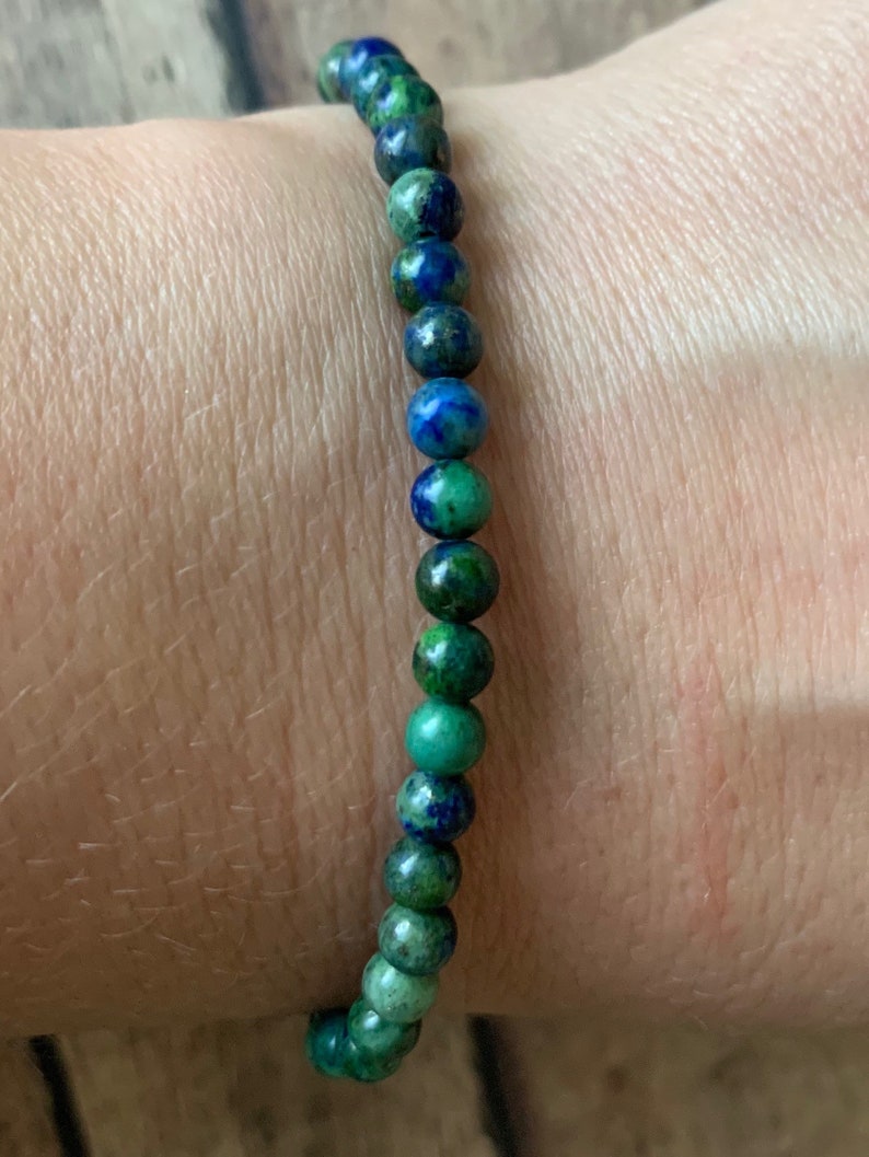 May include: A green and blue gemstone bracelet with small round beads.