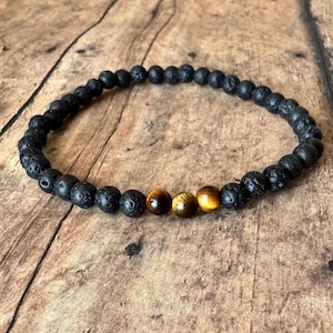 May include: A black lava rock beaded bracelet with three tiger's eye beads.