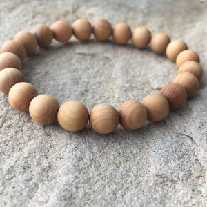 May include: A wooden bead bracelet with natural brown beads. The bracelet is made of smooth, round beads that are strung together on a thin cord.