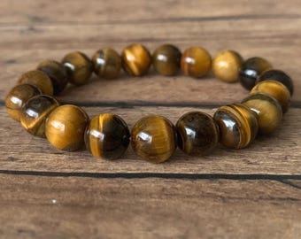May include: A brown and gold tiger's eye beaded bracelet. The bracelet is made of round beads and is strung on elastic.