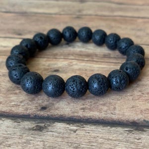 May include: A black beaded bracelet made of lava rock.