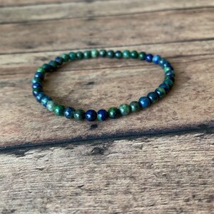 May include: A blue and green gemstone bracelet with small round beads.
