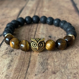May include: A black lava rock and tiger's eye beaded bracelet with a gold owl charm.