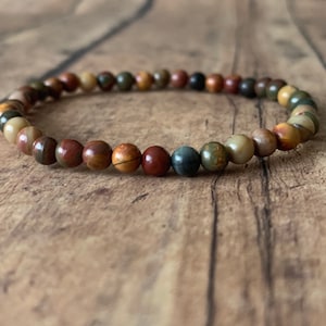 May include: A beaded bracelet with brown, red, and green stones.
