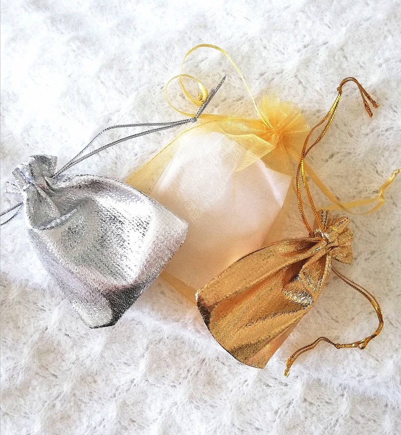 May include: Three small drawstring bags, one silver, one gold, and one white with a sheer, gauzy texture.