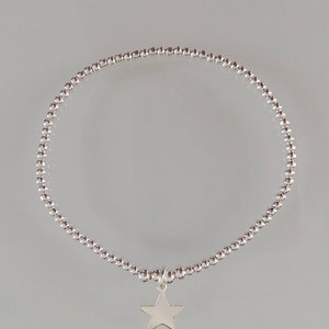 May include: A silver beaded bracelet with a star charm. The bracelet is made of small, round beads and has a simple, elegant design.