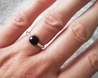 May include: A silver ring with a black square-shaped gemstone.