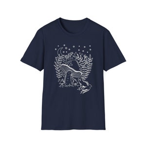 May include: A navy blue t-shirt with a white outline of a mushroom, a frog, and a crescent moon with stars. The design is reminiscent of a fairytale forest.
