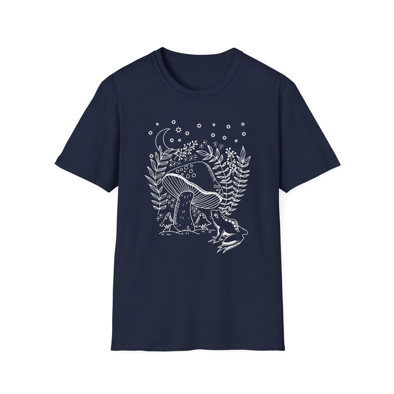 May include: A navy blue t-shirt with a white outline of a mushroom, a frog, and a crescent moon with stars. The design is reminiscent of a fairytale forest.