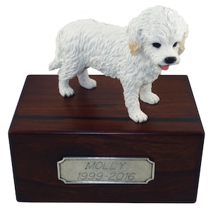May include: A white dog figurine stands atop a dark wooden box with a silver nameplate. The nameplate reads "MOLLY 1999-2016". The dog has a pink tongue and black eyes. The box is rectangular and has a dark wood grain.
