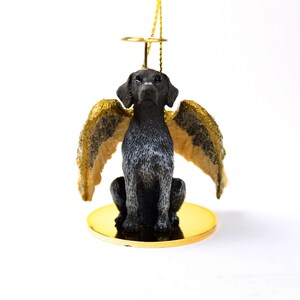 May include: A black and white German Shorthaired Pointer dog figurine with gold wings and a halo, sitting on a gold base. The figurine is an ornament.