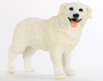 May include: White figurine of a dog with a long, fluffy coat. The dog is standing with its tongue sticking out.