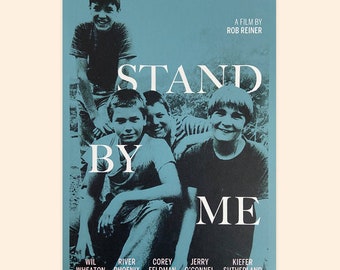 May include: A blue and white movie poster for the film "Stand By Me" featuring a group of four boys. The poster includes the film title, the director's name, Rob Reiner, and the names of the actors: Wil Wheaton, River Phoenix, Corey Feldman, Jerry O'Connell, and Kiefer Sutherland.