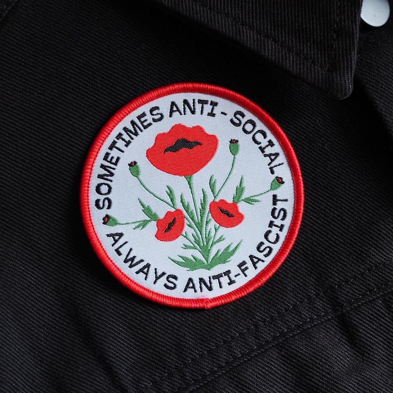 Op de afbeelding: Een witte en rode geborduurde patch met de tekst "Sometimes Anti-Social Always Anti-Fascist" en een ontwerp met een rode klaproos.