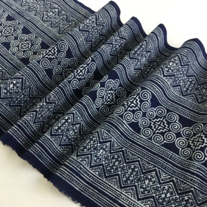 Puede incluir: Tela azul índigo con un patrón geométrico blanco. La tela está doblada y tiene una superficie texturizada.