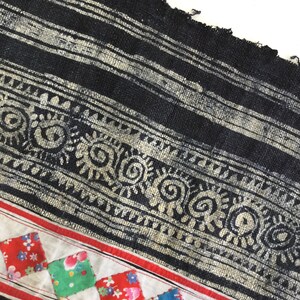 May include: Close-up of a textile with a black and white striped pattern, a decorative border with spiral and floral motifs, and a patchwork section with red, green, and blue floral squares.