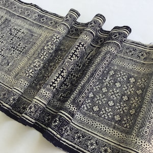 Könnte beinhalten: Ein weißer Stoff mit einem schwarzen geometrischen Muster. Der Stoff ist gefaltet und zeigt die komplizierten Details des Designs.
