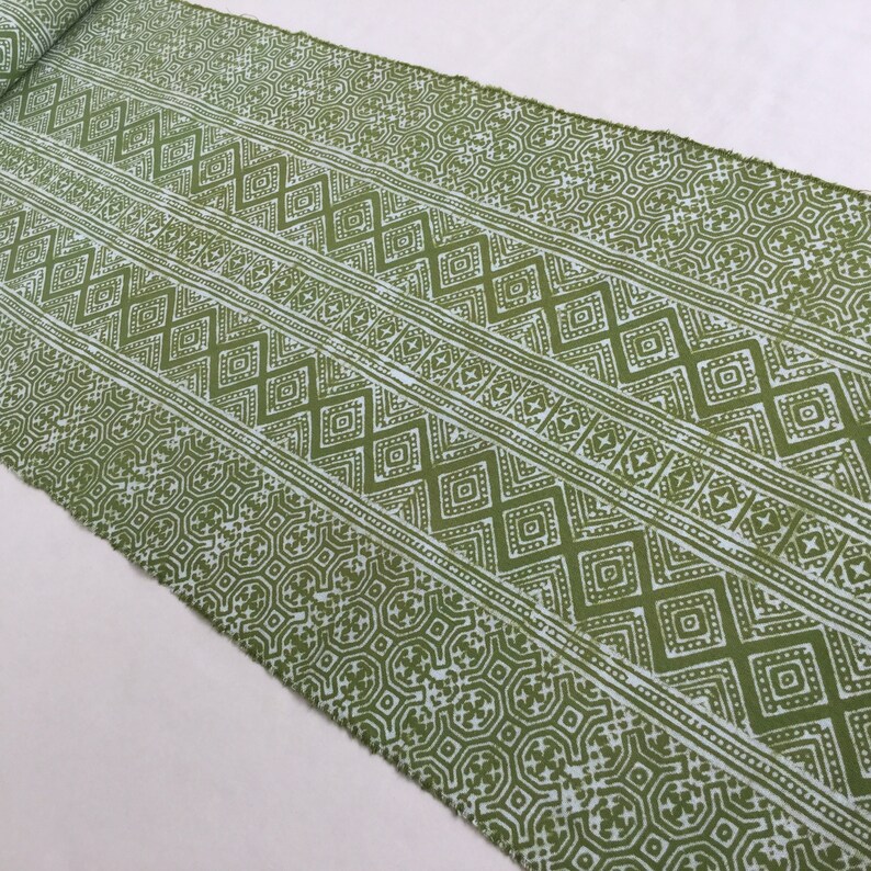 Pu&ograve; includere: Tessuto verde con un motivo geometrico bianco. Il motivo &egrave; composto da quadrati, rombi e triangoli ripetuti.