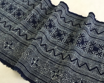 May include: Indigo blue fabric with a white geometric pattern. The fabric has a frayed edge and is folded in a way that shows the pattern.