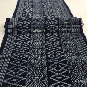 May include: Indigo blue fabric with a white geometric pattern. The fabric is folded in several layers, showing the pattern on both sides.