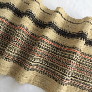 May include: A woven fabric with black and red stripes. The fabric is made of natural fibers and has a rustic look.